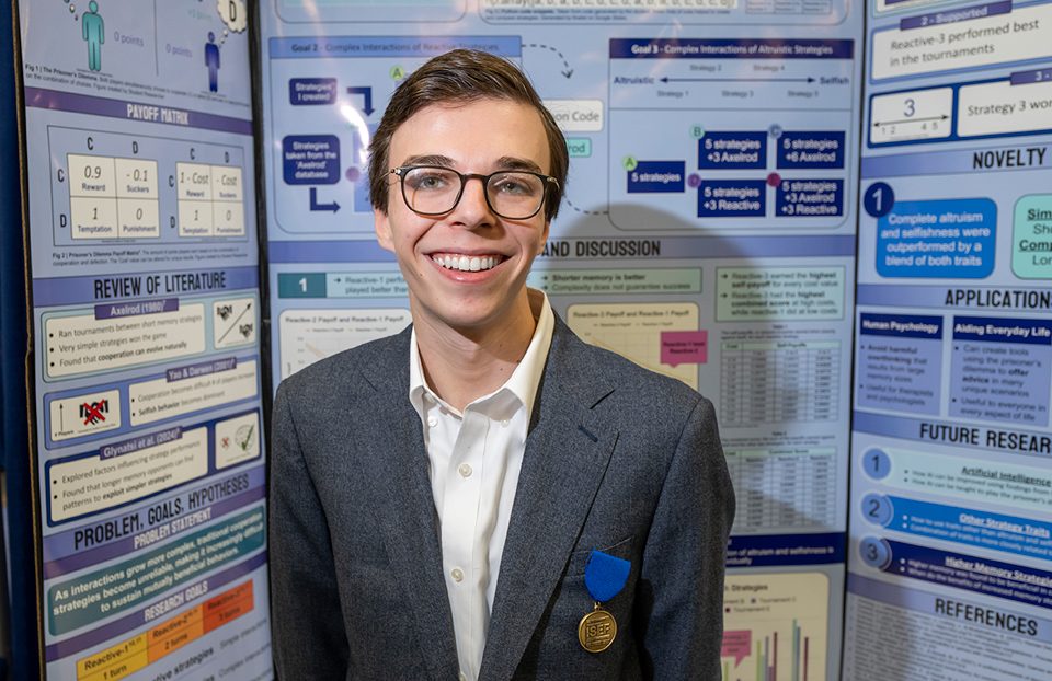 ISEF finalist with award medal standing at the project booth